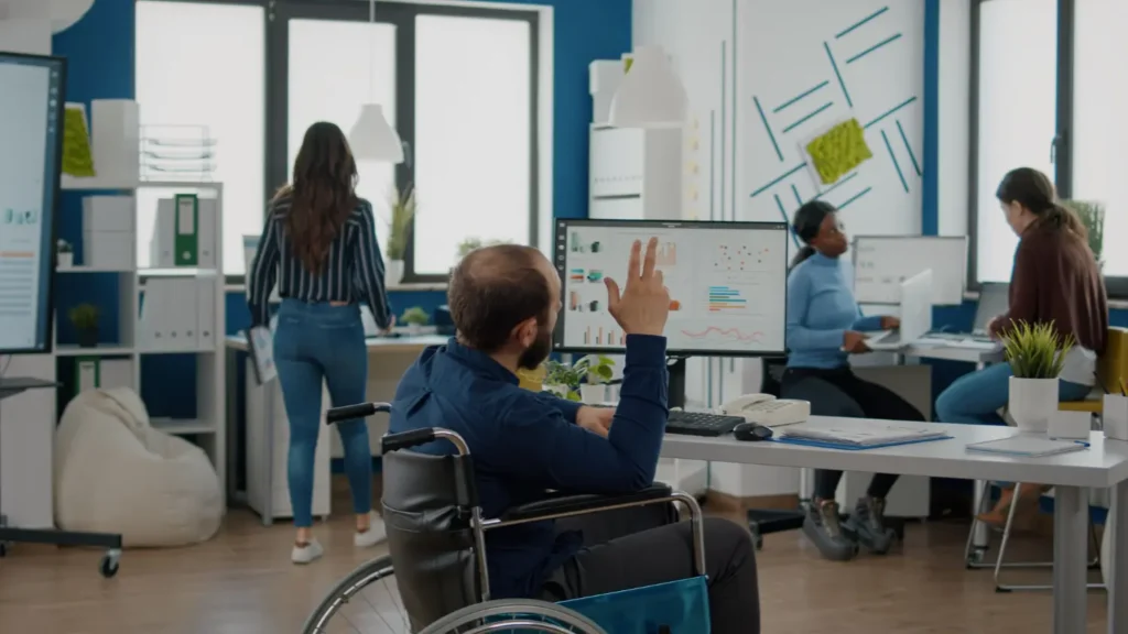 Persona con discapacidad trabajando en oficina junto a su equipo en un entorno laboral inclusivo dentro de un centro especial de empleo